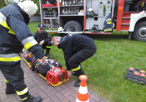 Strażacy na terenie przedszkola prezentują wyposażenie i przeznaczenie sprzętu w jaki jest wyposażony bojowy wóz strażacki