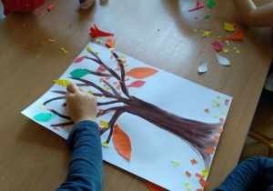 Dzieci wykonują w zespołach prace plastyczne pt. „Jesienne drzewo"