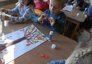 Dzieci wykonują w zespołach prace plastyczne pt. „Jesienne drzewo"