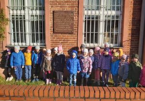 Przedszkolaki przed tablicą upamiętniającą na budynku Poczty Polskiej.